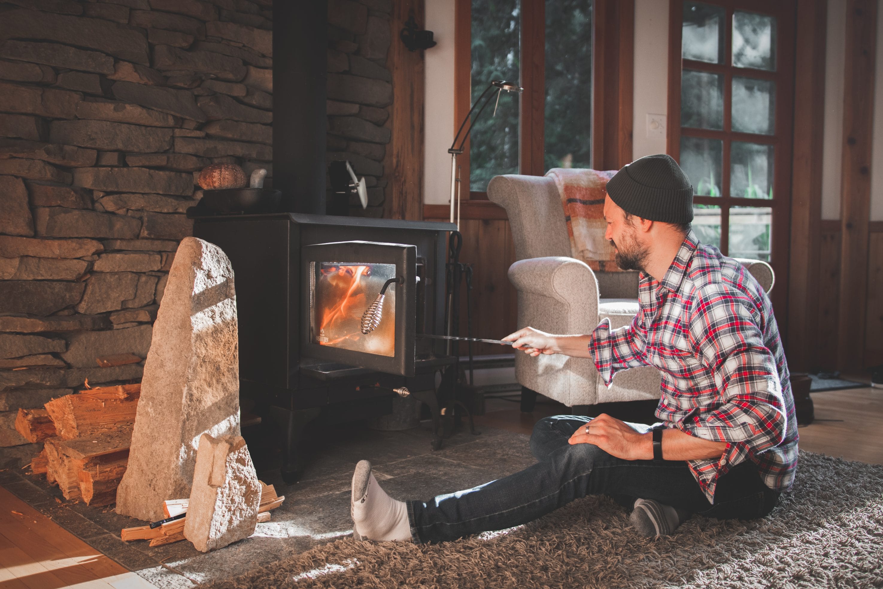 A homeowners adds a wood log to his wood stove.